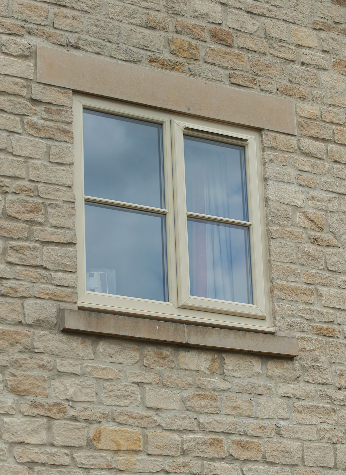 uPVC beige flush and casement window on a brick wall